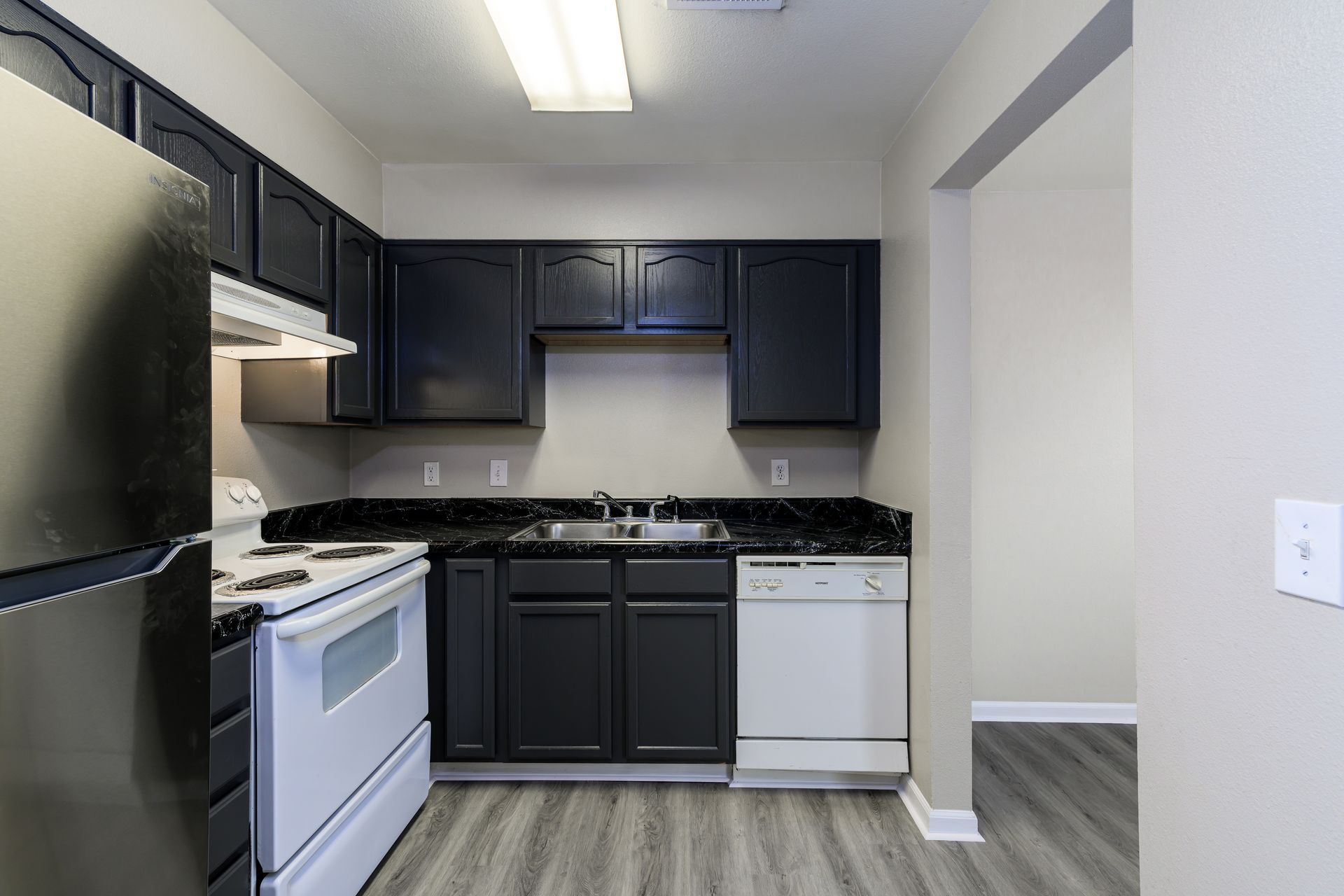 A kitchen with black cabinets and white appliances