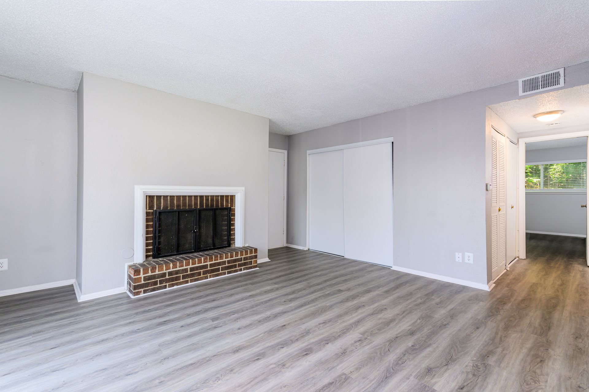 An empty living room with a fireplace and hardwood floors.