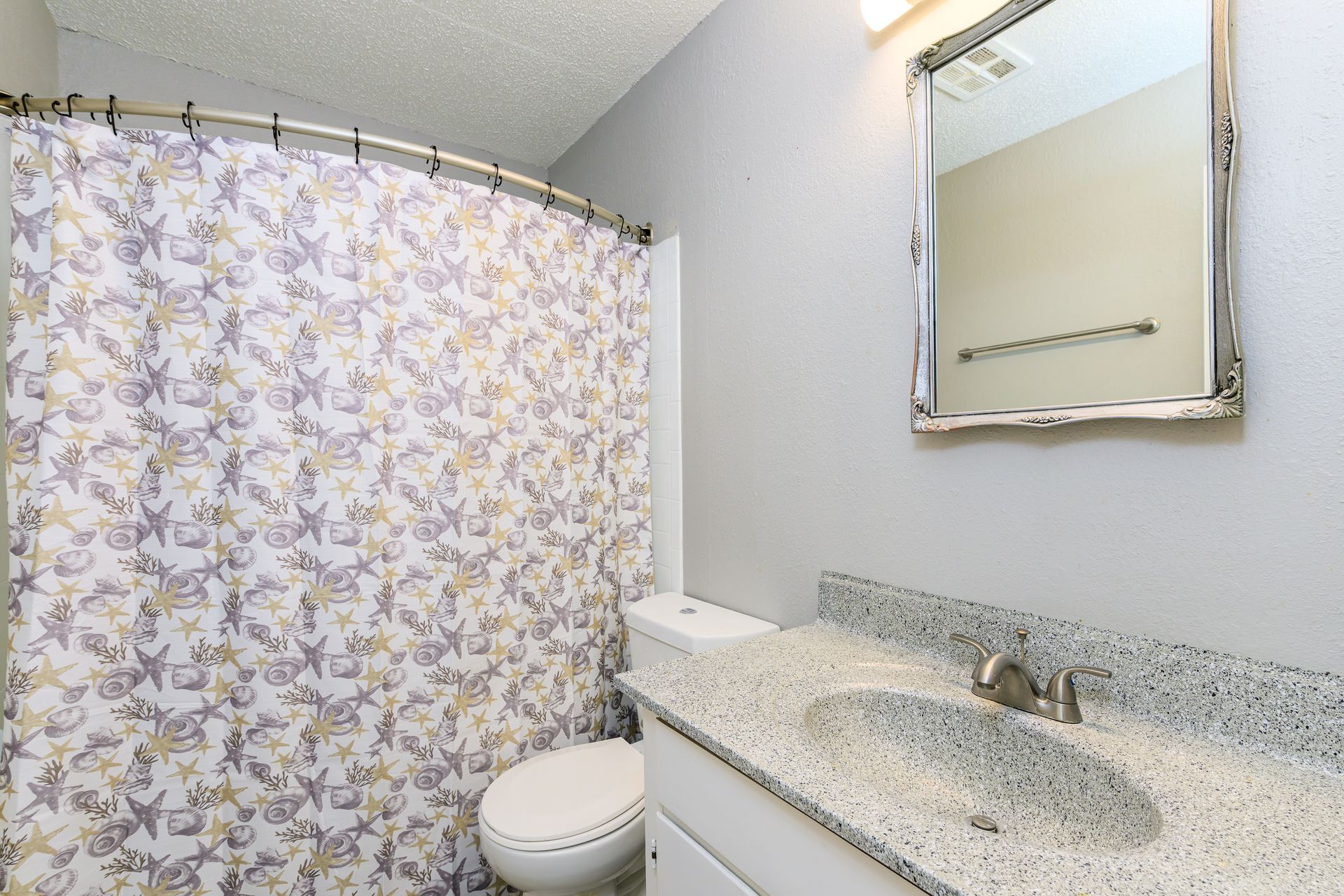 A bathroom with a toilet a sink and a shower curtain