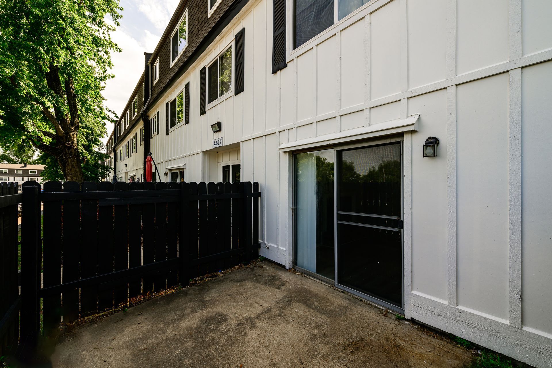 A white building with a black fence and a sliding glass door.
