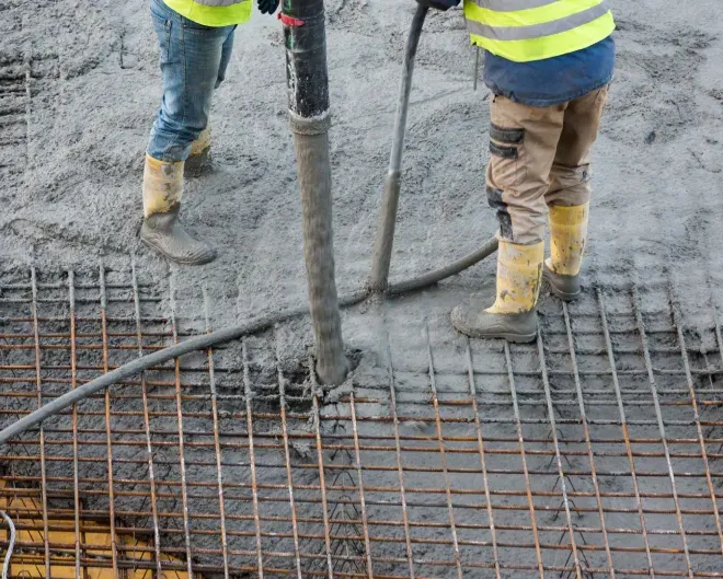 Construction workers pouring concrete over steel rebar at a site