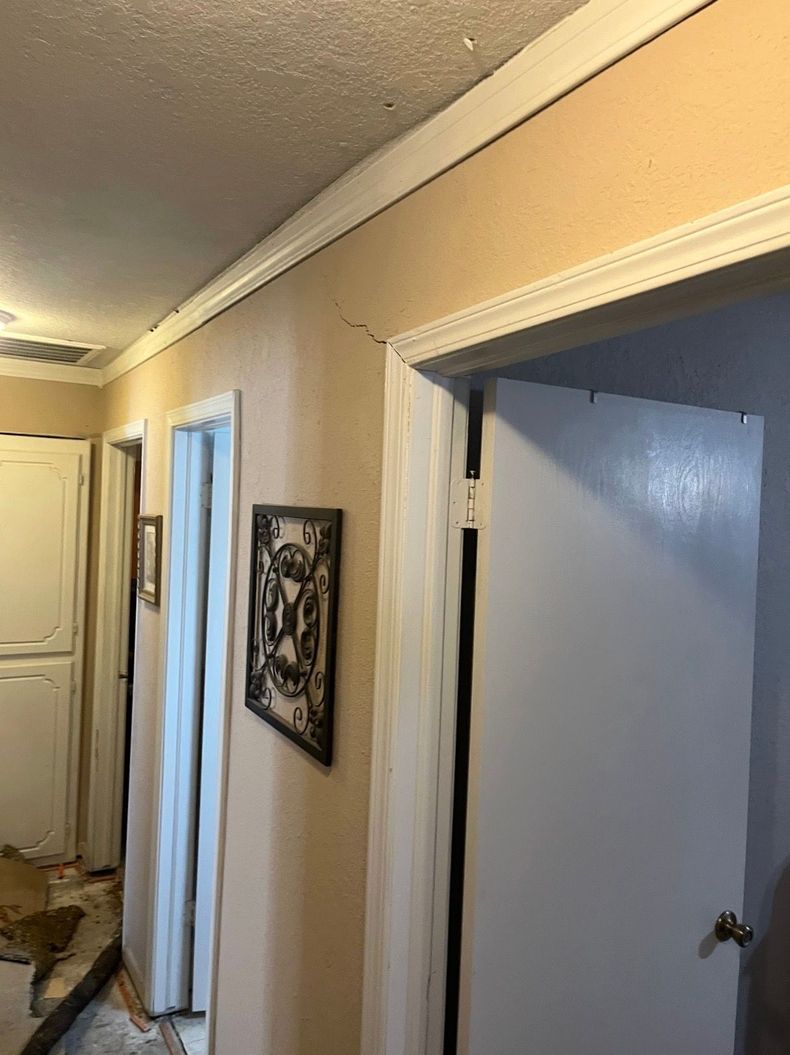 Narrow hallway with beige walls, white doors, and a decorative wall hanging