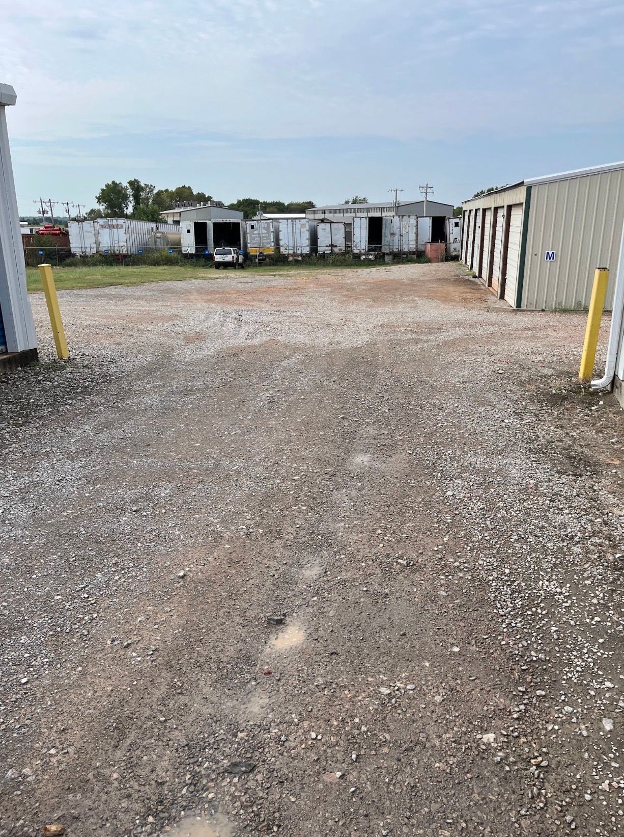 Gravel lot between white storage containers under a cloudy sky