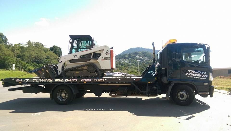 Black Tow Truck With White Bobcat on Flatbed, Outdoors on a Sunny Day — Tigo’s Towing In Cairns City, QLD