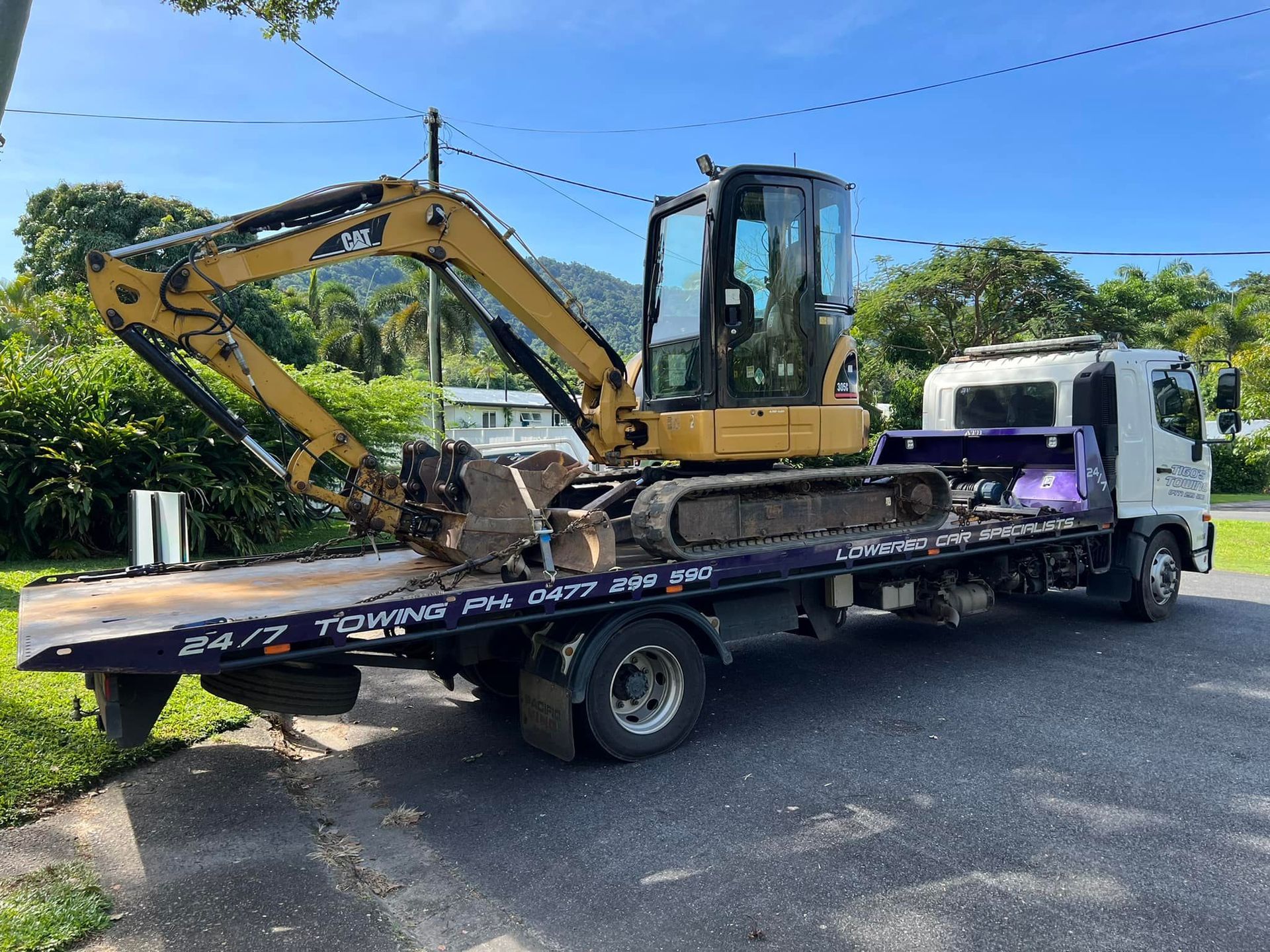 A Yellow Excavator on a Flatbed Tow Truck on a Road — Tigo’s Towing In Cairns City, QLD