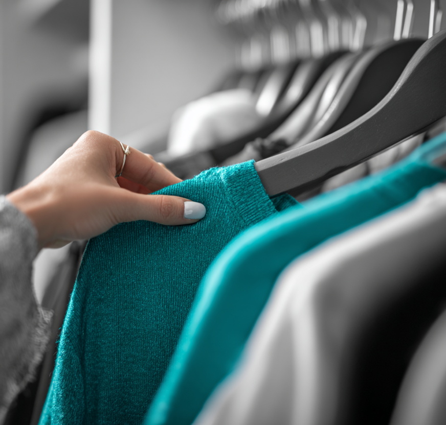Selezione manuale di un maglione color verde acqua da uno scaffale dell'armadio.
