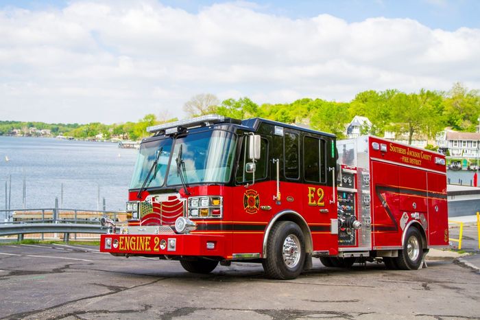 Red fire truck parked by a waterfront on a sunny day