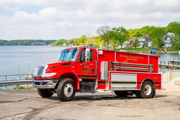 Red fire rescue truck parked by a waterfront road on a sunny day