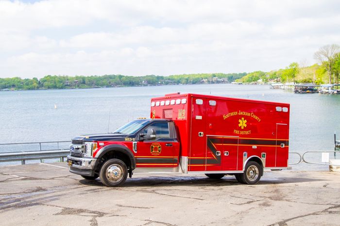 Red emergency medical truck parked by a waterfront pier