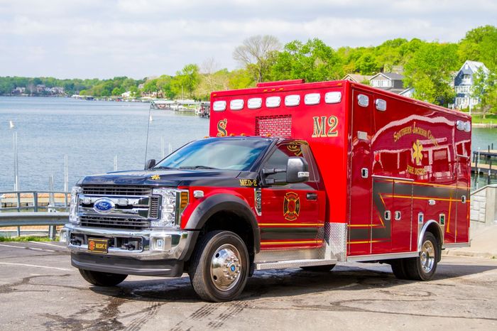 Red ambulance parked by the waterfront on a sunny day