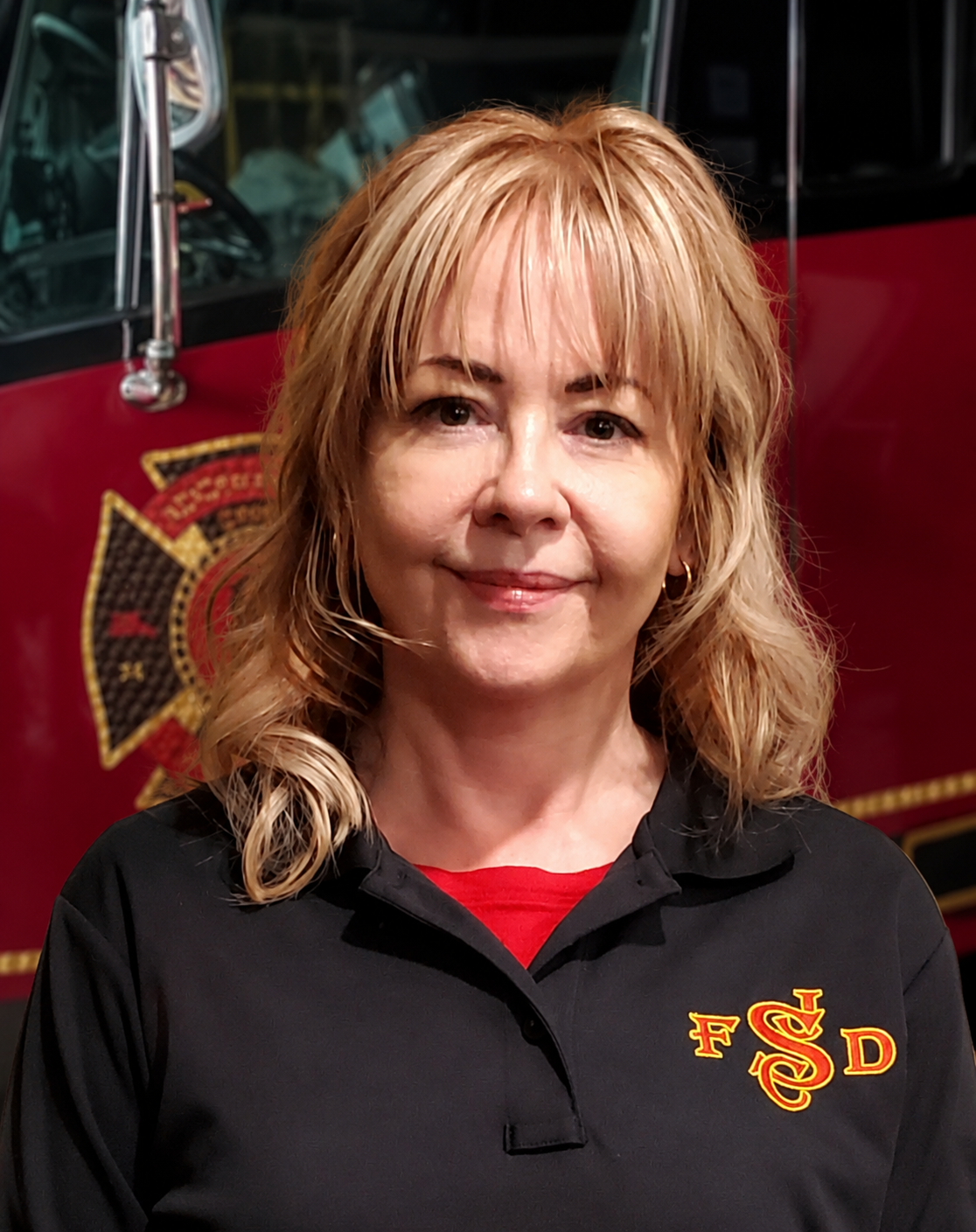 Portrait of a woman in a black FSD polo, standing before a fire truck