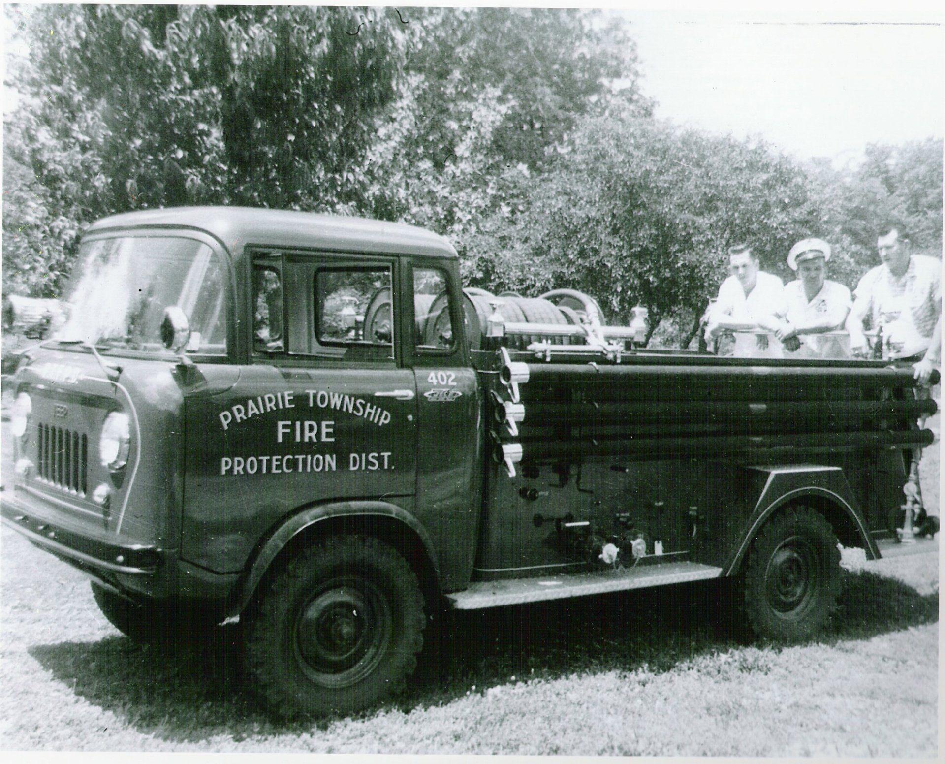 Vintage fire protection truck parked outdoors with people seated in the back