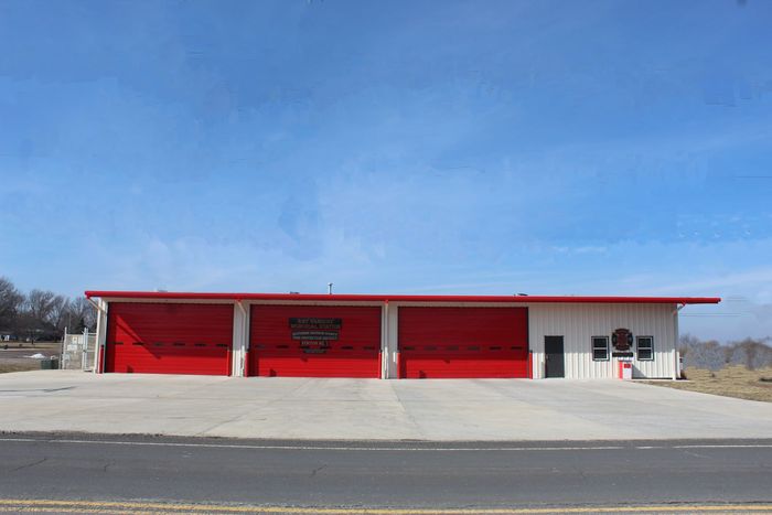 Red roadside building with garage doors under a clear blue sky