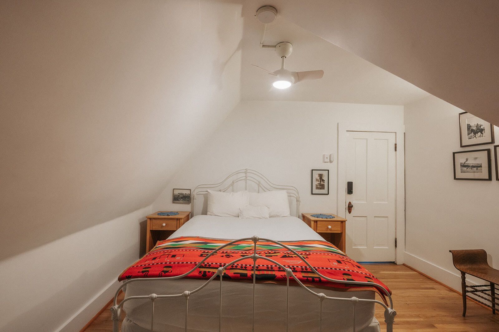 Cozy attic bedroom with a white bed, red blanket, ceiling fan, and sloped walls