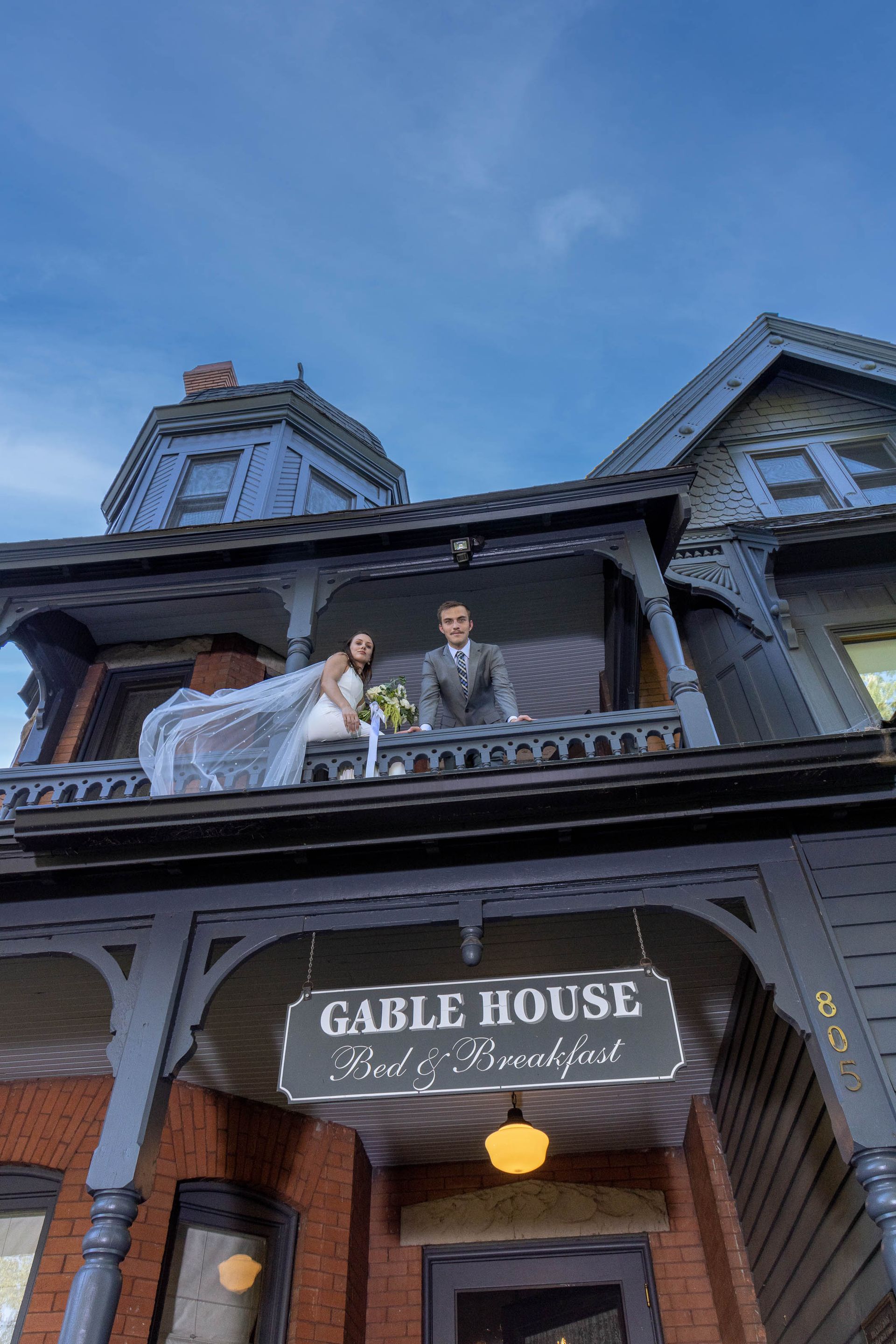 People standing on a balcony above the Caddie House sign at dusk