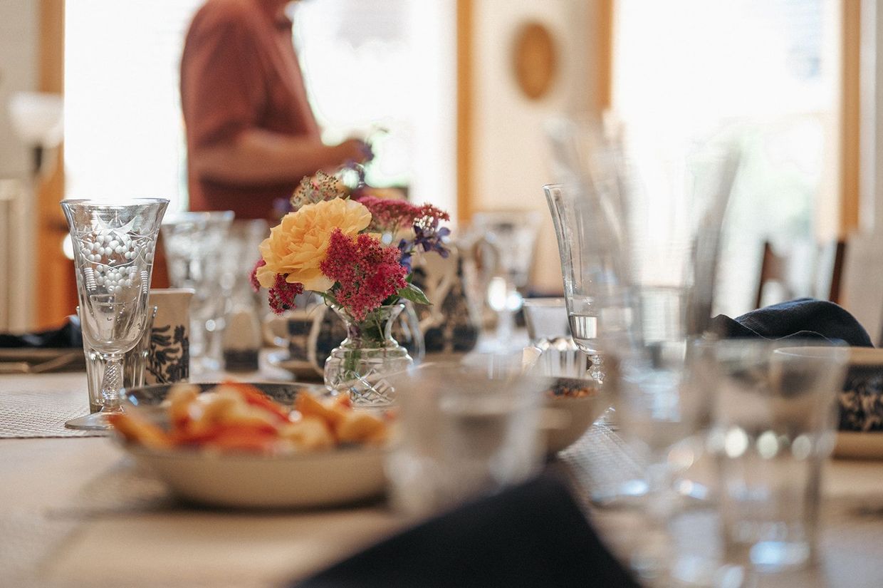 Set dining table with flowers, glasses, and plates in a softly lit room