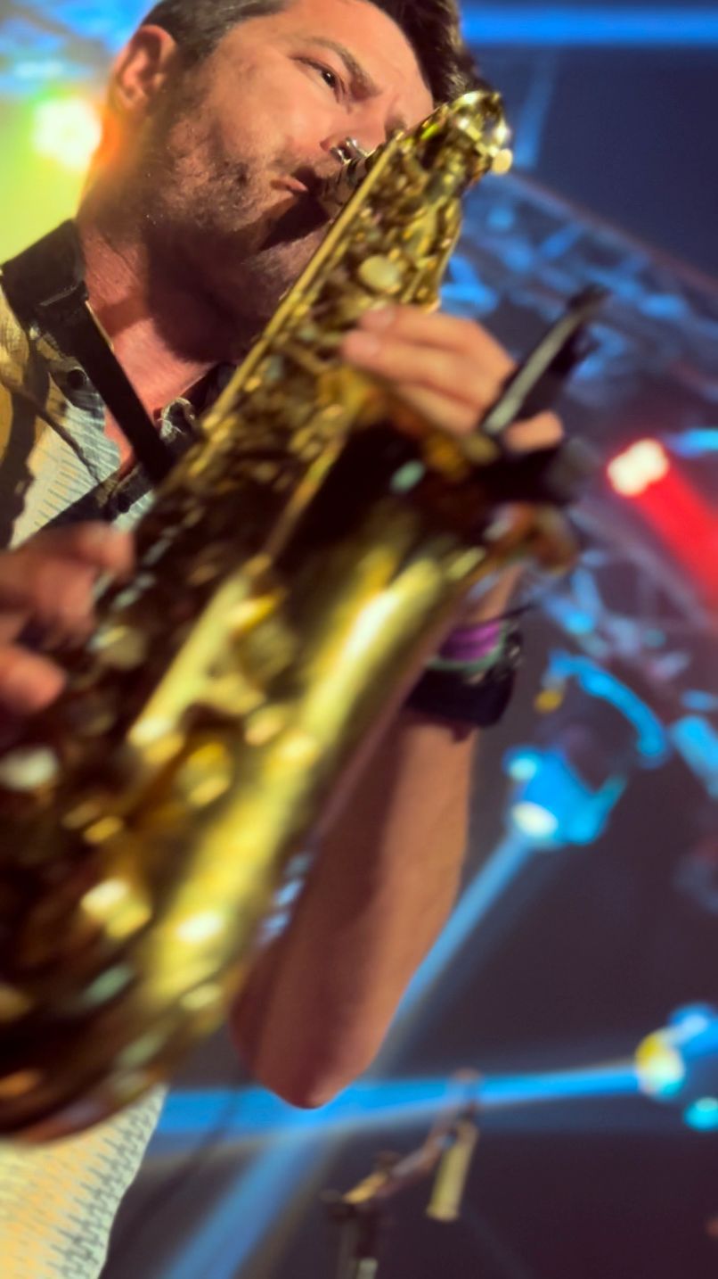 Saxophonist performing on stage under colorful blue and red lights, close-up view