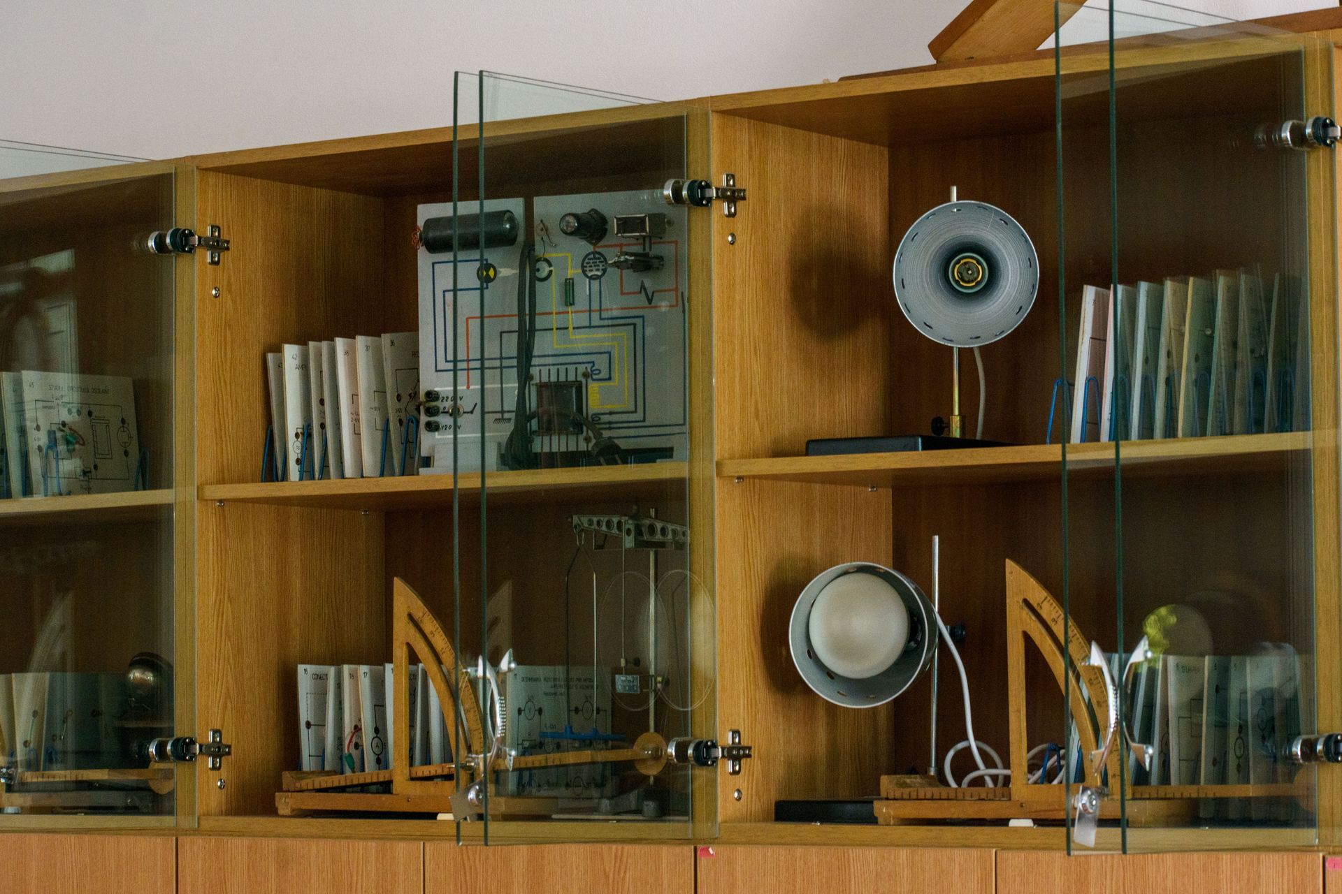 Wooden shelves with glass doors holding books and decorative speakers in a room