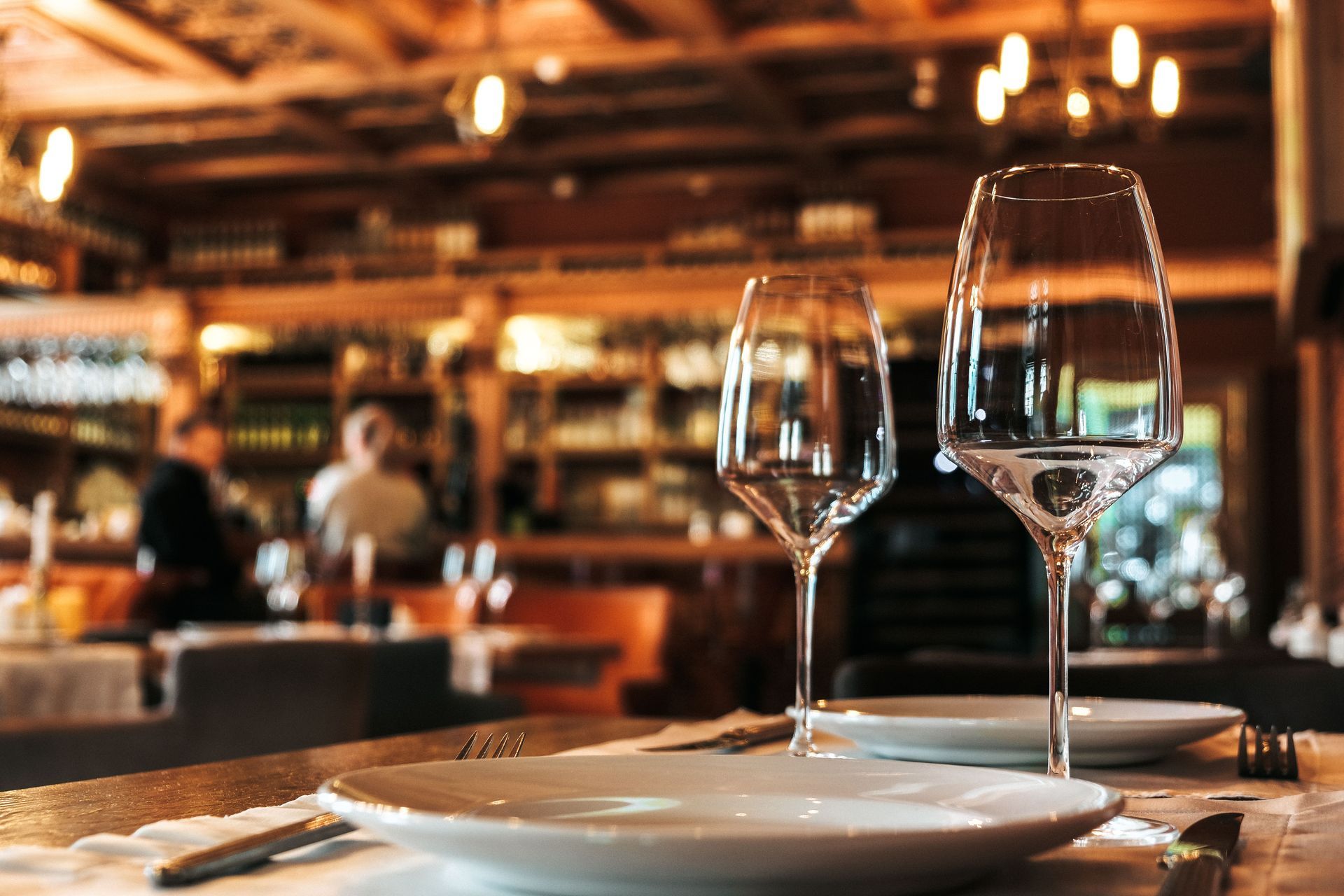 Set dining table in a warm, rustic restaurant with wine glasses and plates