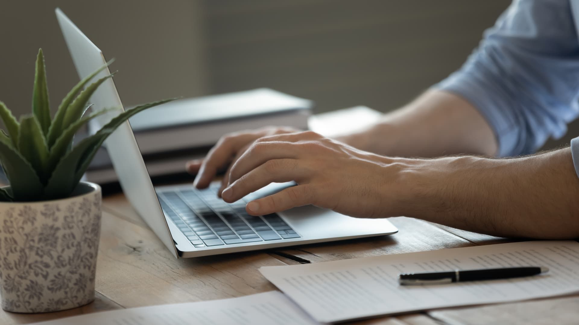 A man is typing on a laptop computer at a desk.