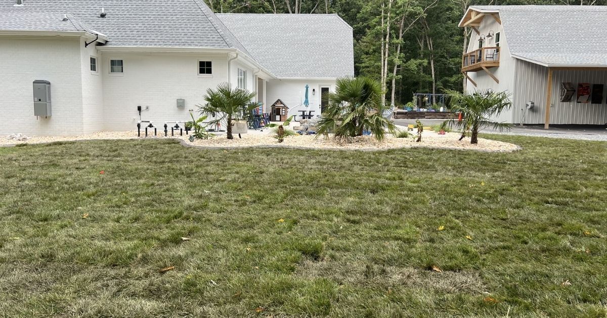 Finished Clover SC backyard landscaping with sod, river rock, decorative curbing and poolside plantings