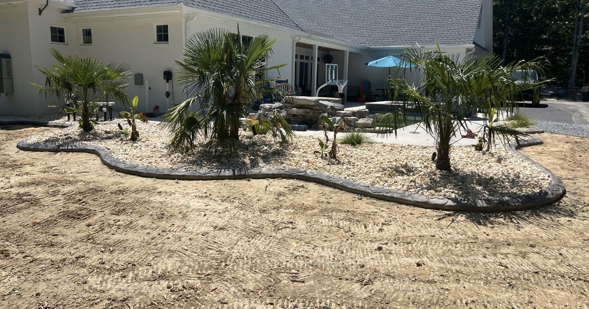 Decorative concrete curbing and river rock around poolside landscape beds in Clover SC