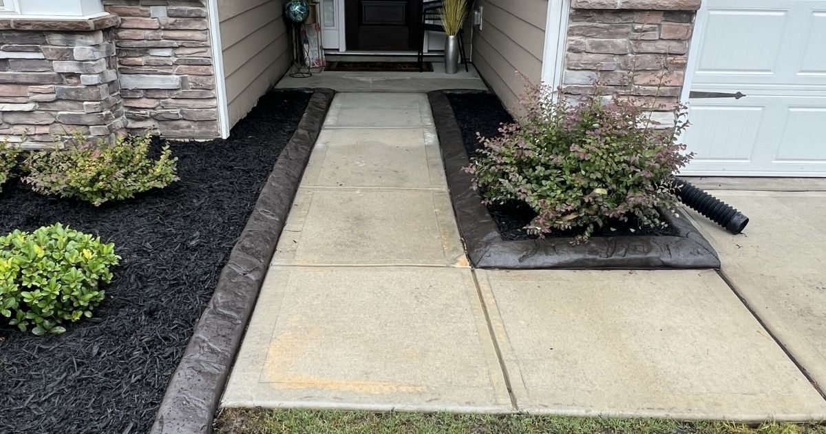 Decorative concrete curbing and river rock around poolside landscape beds in Clover SC