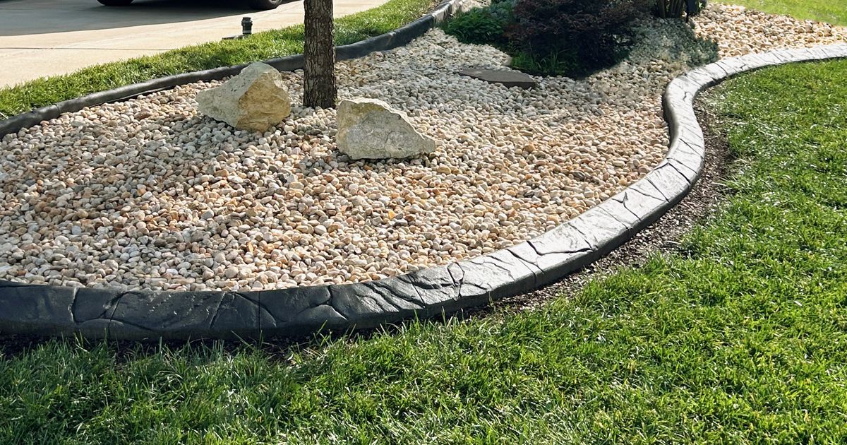 Curved stone border around a gravel bed beside a green lawn and walkway