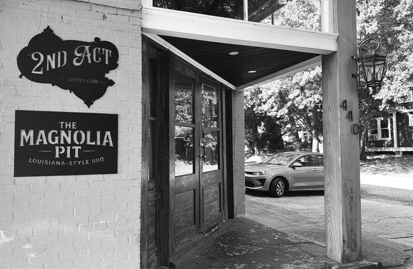 Entrance to The Magnolia Pit on 2nd Ave, with a parked car under a covered walkway