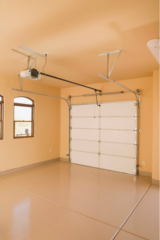 An empty garage with a white garage door and a garage door opener.