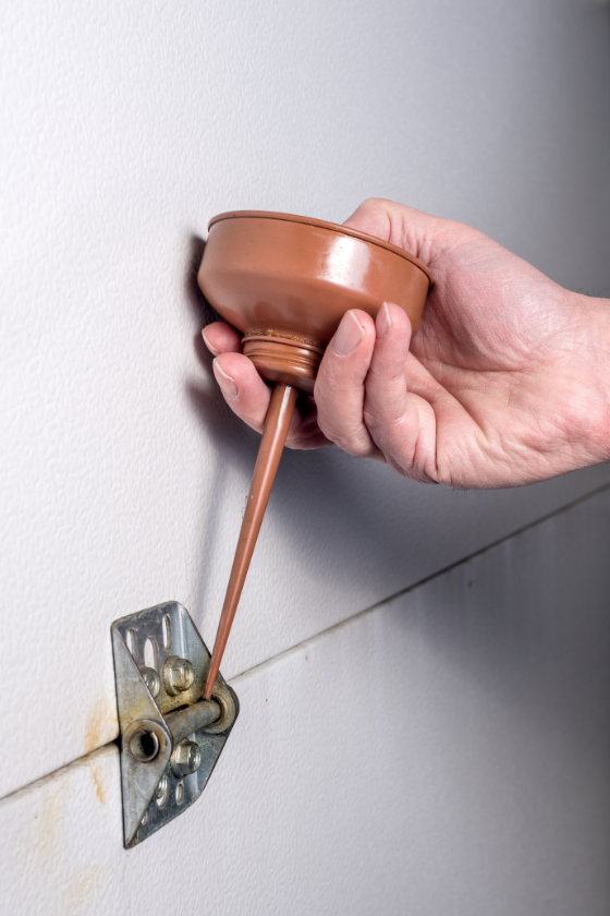 A person is pouring something into a hole in a wall