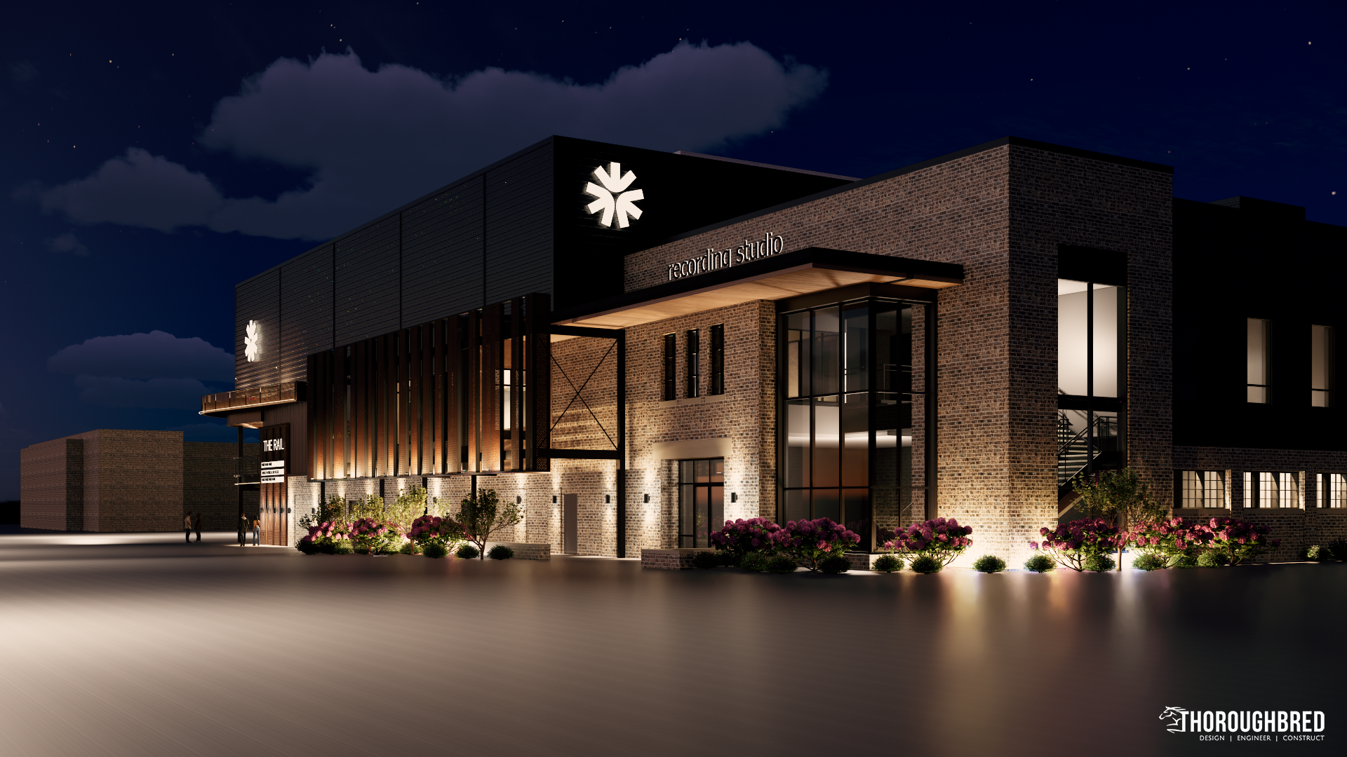 Night view of a modern brick building lit by warm lights; a large floral emblem on the upper facade.