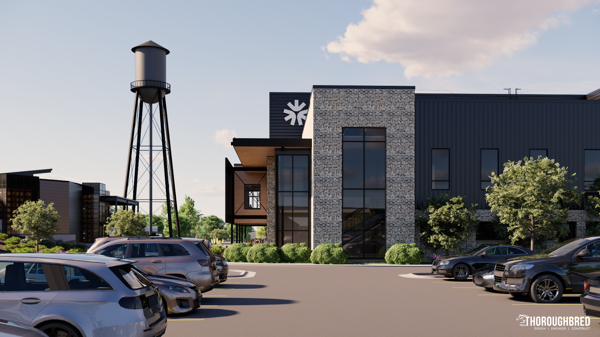 Modern office building with dark siding and brick, parking lot, and water tower.