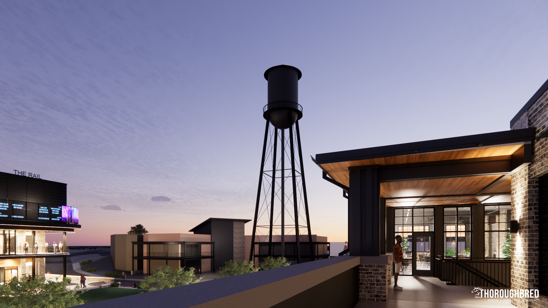 Nighttime view of a modern building with a water tower in the background and a person standing on a patio.