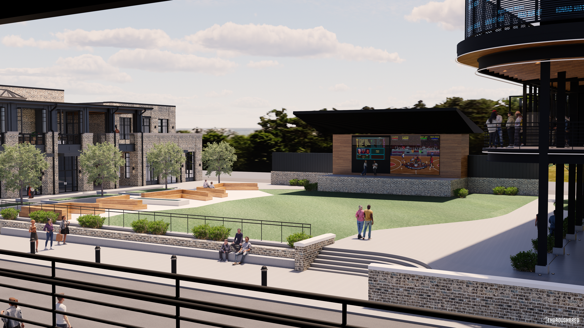 Outdoor event space with stage, lawn, seating, and buildings. Two people are walking on the grass.