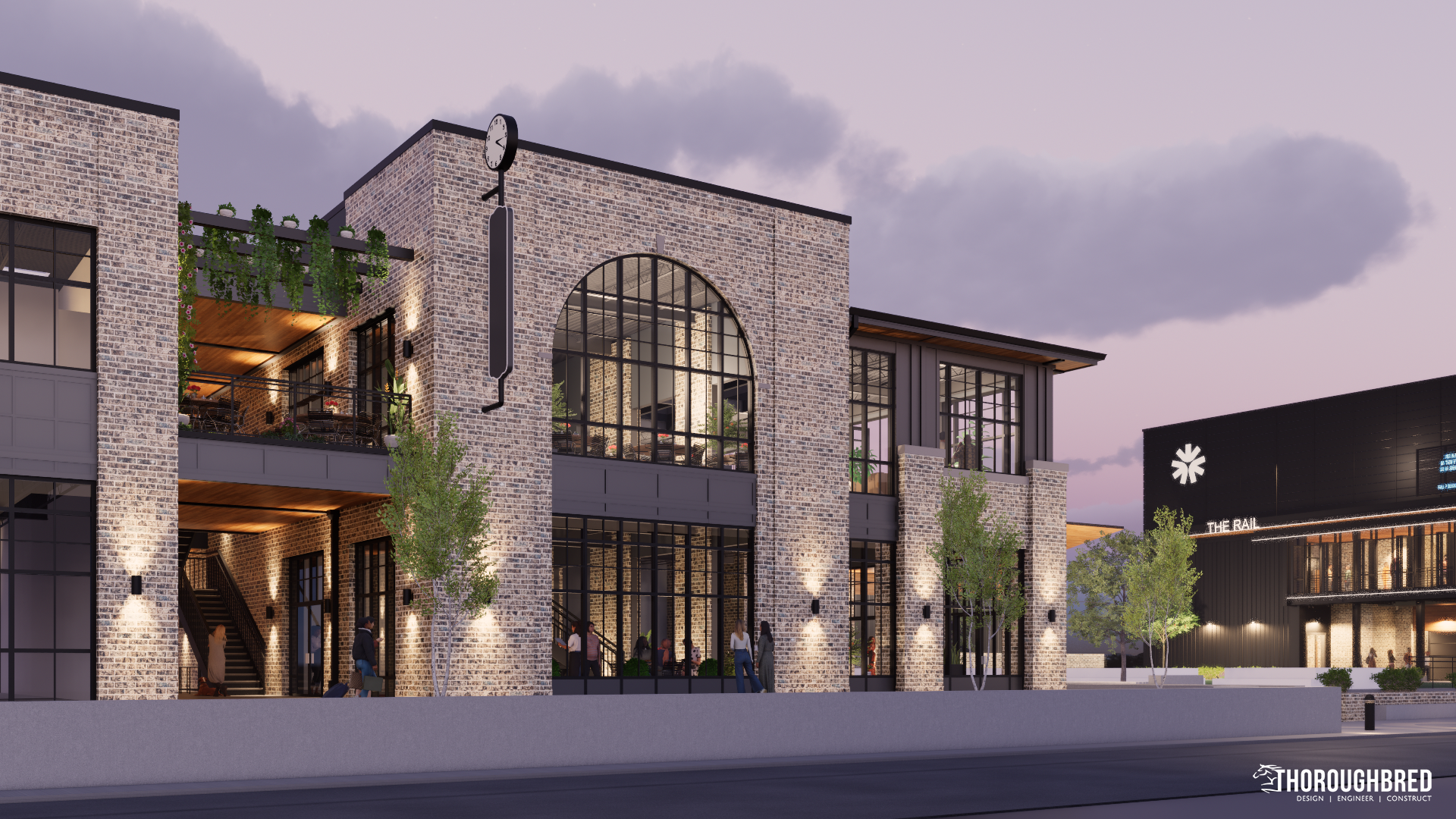 Exterior view of modern brick building with arched windows, outdoor seating, and streetlights at dusk.