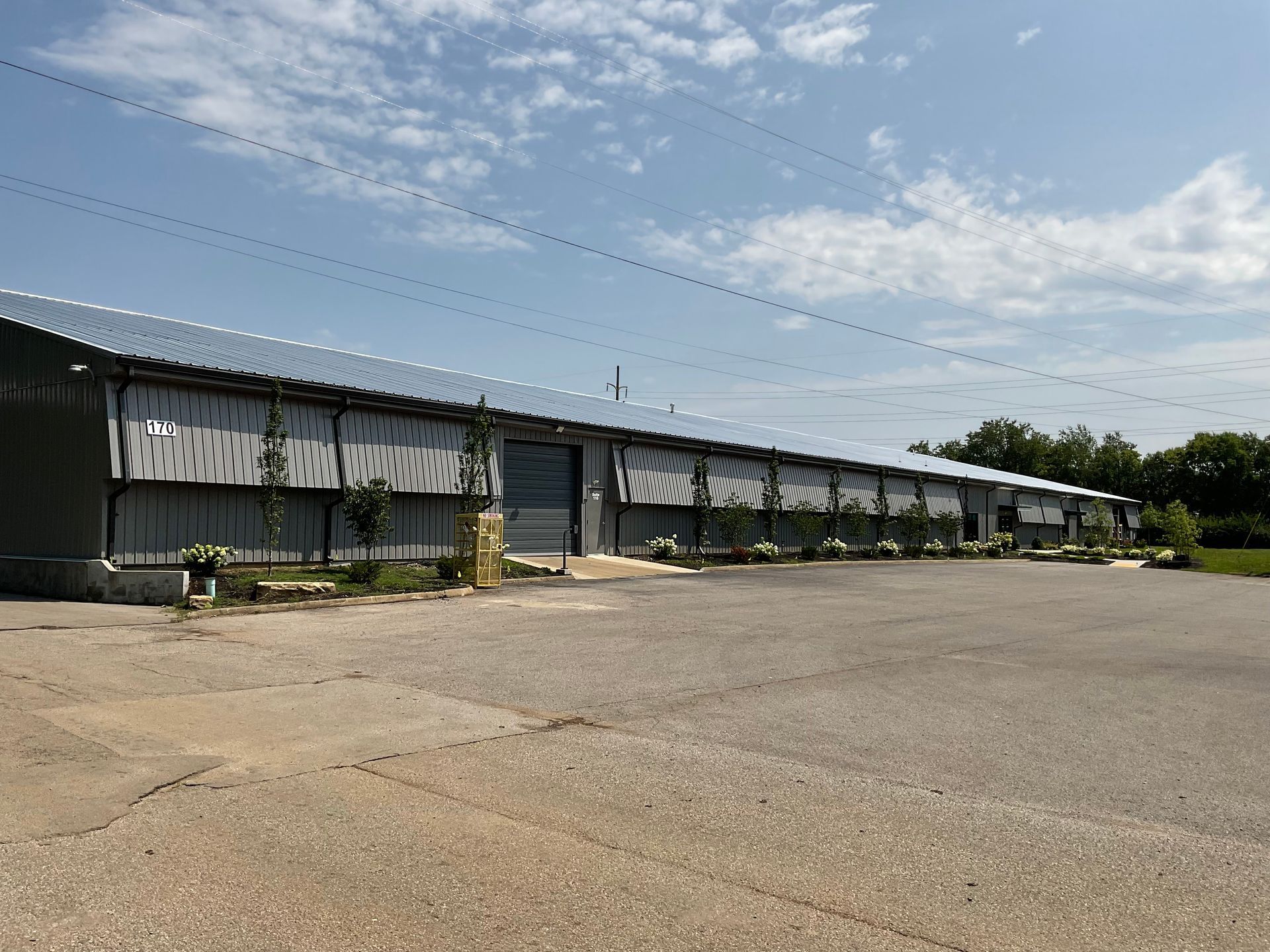 A long, metal building with multiple garage doors on a sunny day.