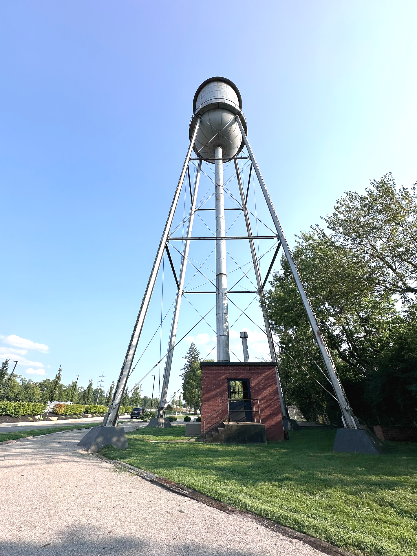 Water tower with metallic frame and red brick base against a blue sky.