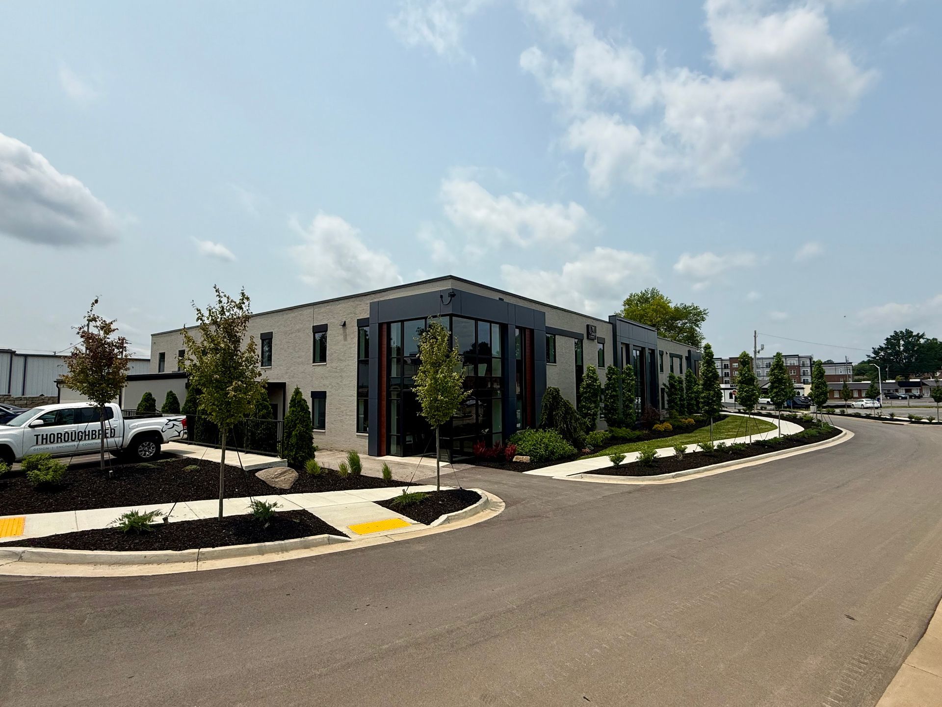 Modern building with brick and large windows, landscaping and a circular driveway.