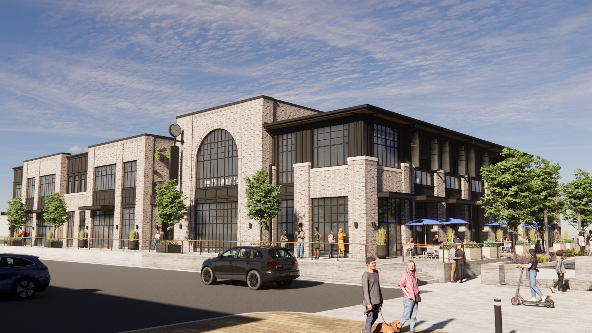 Brick commercial building with arched window and outdoor seating area. Blue sky, cars, and pedestrians.