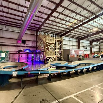 Indoor race track with a large wooden structure, featuring curves and signage.