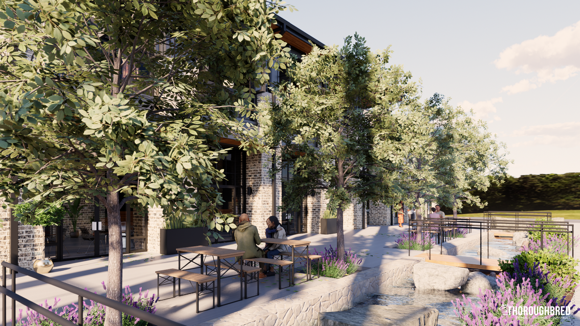 Stone building with outdoor seating next to a water feature, trees, and sky.