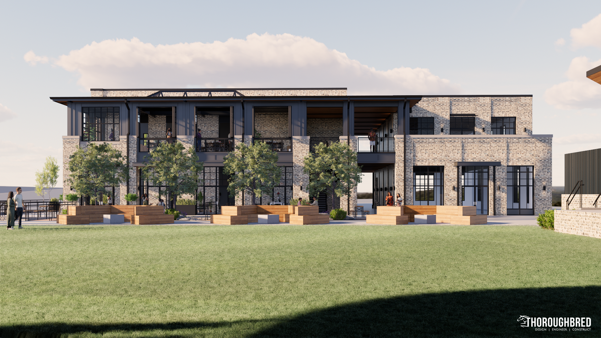 Modern brick building with glass windows, green lawn, trees, and benches. Sunny day.