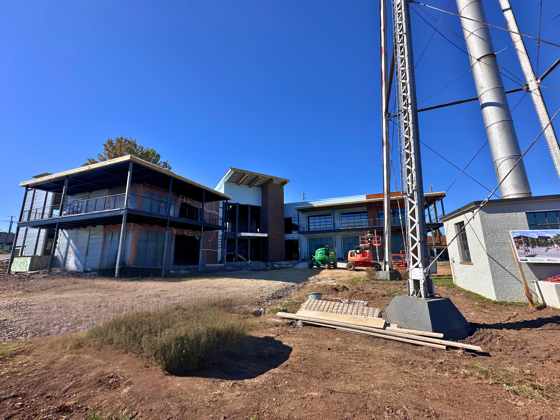 A large house is being built in the middle of a dirt field.
