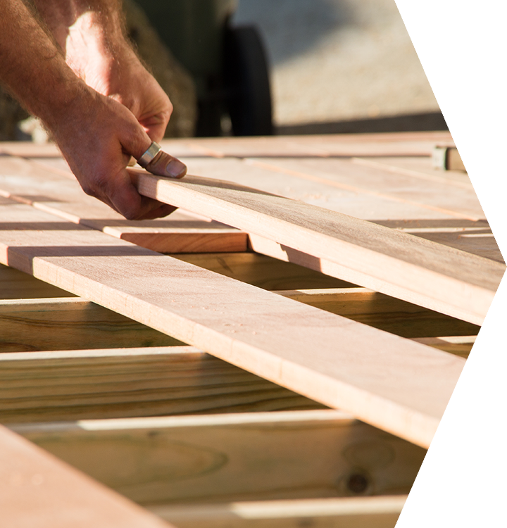 Hand placing a wooden slat onto a sunlit frame during construction. Hand placing a wooden slat onto a sunlit frame during construction.