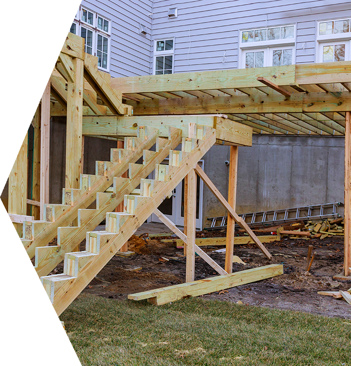 Wooden outdoor staircase under construction beside a house, with support beams and a raised deck. Wooden outdoor staircase under construction beside a house, with support beams and a raised deck.