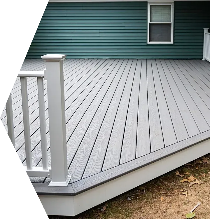Gray composite deck with white railing beside a teal house wall and window Gray composite deck with white railing beside a teal house wall and window