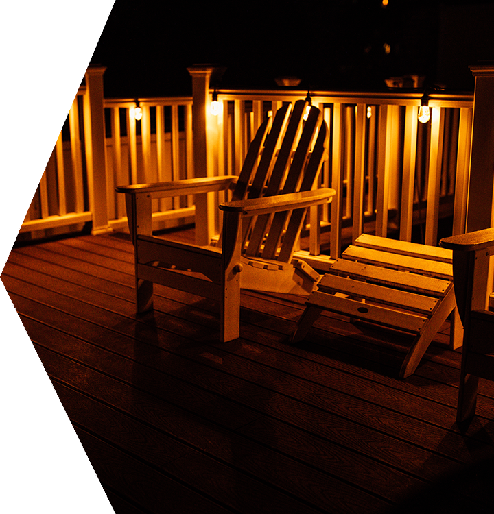 Warmly lit wooden deck with two Adirondack chairs at night Warmly lit wooden deck with two Adirondack chairs at night