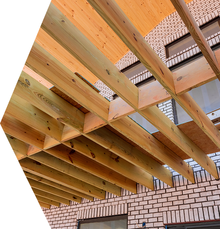 Wooden roof beams under construction above a brick building exterior Wooden roof beams under construction above a brick building exterior