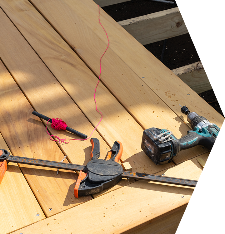 Wood deck under construction with hammer, clamps, tape measure, and cordless drill. Wood deck under construction with hammer, clamps, tape measure, and cordless drill.